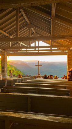 people sitting in pews at the end of a church with mountains in the background