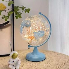 an illuminated globe on top of a table next to a small teddy bear and plant