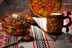 there is a bowl of food on the table next to two cups and spoons