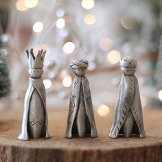 three small metal figurines sitting on top of a wooden table next to a christmas tree