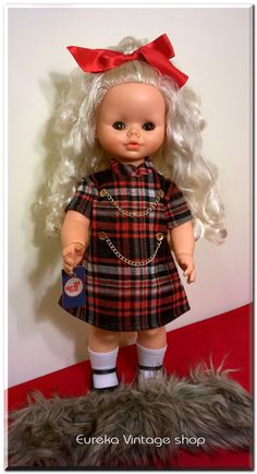 a doll with blonde hair wearing a plaid dress