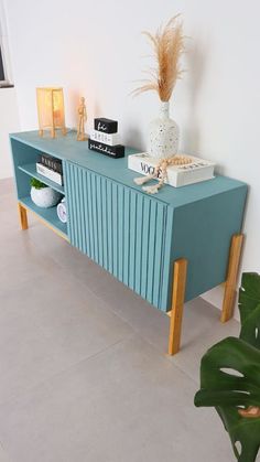 a blue console table with books on it and a plant in the corner next to it