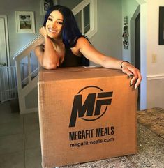 a woman sitting on top of a cardboard box in the middle of a room with stairs