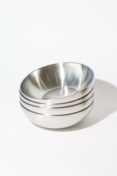 three metal bowls sitting side by side on a white surface with one empty bowl in the middle