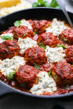 a pan filled with meatballs covered in sauce and parmesan cheese on top