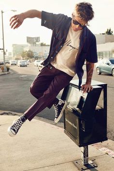 a man on a skateboard does a trick in the air over a trash can