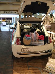 an open hatchback car with its trunk filled with blankets and other items sitting on the floor