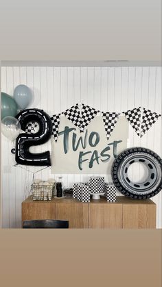a birthday party with balloons, race cars and streamers for two fast sign on the wall