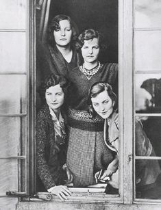 four women are standing in an open window