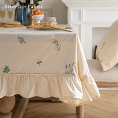 the table is covered with white linens and has an embroidered flower design on it