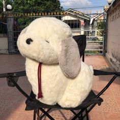 a white stuffed animal sitting on top of a black chair