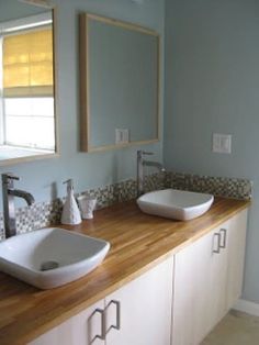 two white sinks sitting on top of a wooden counter