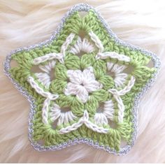 a green and white crocheted star ornament sitting on top of a furry surface