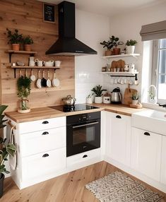 a kitchen with white cabinets and wooden shelves filled with potted plants on the wall