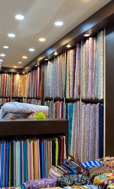 there are many fabrics on display in the store and one person is laying on the bed