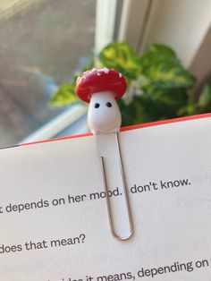 a bookmark with a red mushroom on it and a note attached to the end