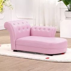 a pink couch sitting on top of a white rug next to a potted plant