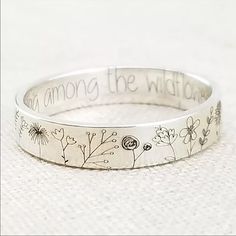 a silver ring with flowers and the words, among the wildflowers on it