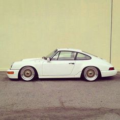 a white sports car parked in front of a yellow wall with gold rims on it