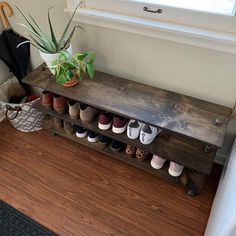 a shoe rack with many pairs of shoes on it next to a window and potted plant