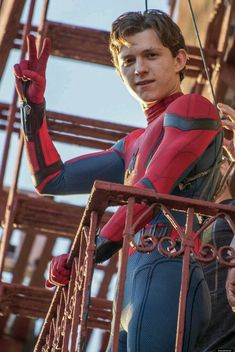 spider - man standing on top of a metal structure with his hands in the air