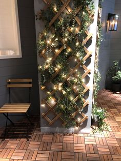 a wall with lights on it and some plants growing up the side of it in front of a bench