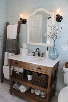 a white toilet sitting next to a bathroom sink under a mirror and a wooden ladder