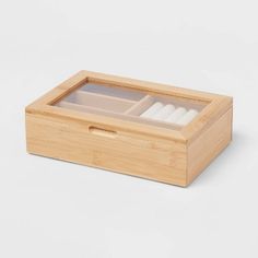 an empty bamboo box with four white candles in it on a white surface, the lid is open