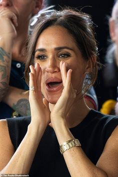 a woman with her hands on her face in front of an audience at a sporting event