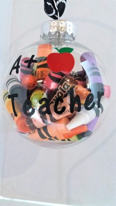 a glass ornament with an apple and teacher's name on it, hanging from a wall