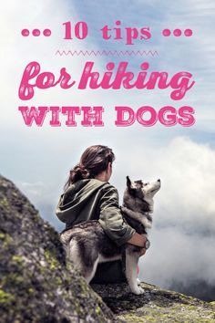 a woman sitting on top of a mountain with her dog looking out at the clouds