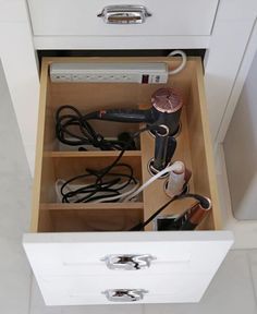 an open drawer with hair dryers and other items in it
