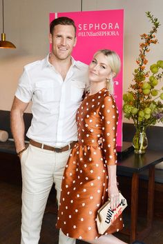 a man and woman standing next to each other in front of a pink sign that says sephora