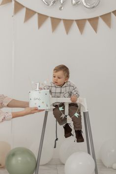 a baby sitting in a high chair holding a cake