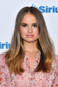 an image of a woman with long hair and brown eyes posing for the camera in front of