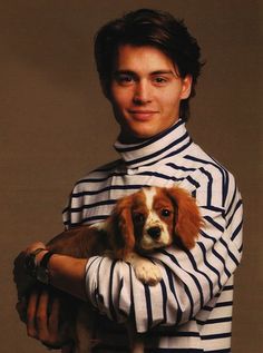 a man holding a dog in his arms and wearing a striped shirt with long sleeves