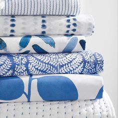 a stack of blue and white bedding on top of each other in different patterns