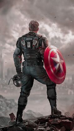 a man with a captain america shield standing on top of a rocky hill in front of a cloudy sky