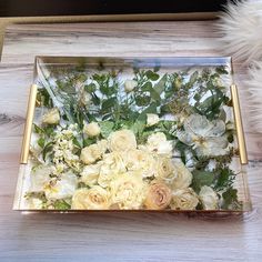 a glass box filled with flowers on top of a wooden table