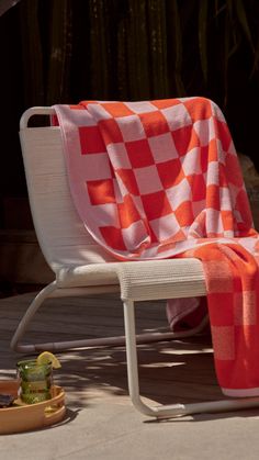 an orange and white checkered blanket sitting on top of a chair next to a basket