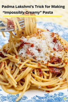 pasta with bacon and parmesan cheese is being served on a blue and white plate