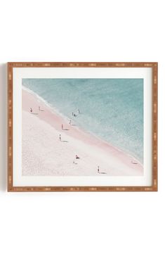 people are walking on the beach in front of blue water and white sand, framed art print