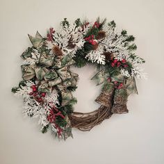 a christmas wreath hanging on the wall next to a white wall with snowflakes and evergreens