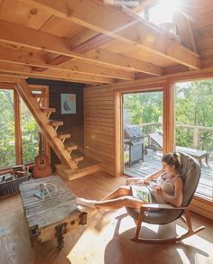 a woman sitting in a chair on top of a wooden floor next to a window