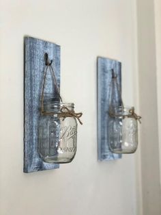 two mason jars are hanging on the wall