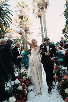 a bride and groom are walking down the aisle after their wedding ceremony in palm trees