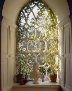 an arched window with potted plants on the ledge and vases in front of it