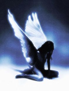 a woman sitting on the ground with her wings spread out in front of her face