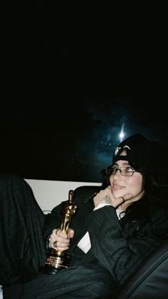 a woman sitting in a car holding an oscar for her role as the lead actress