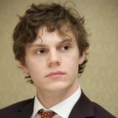 a young man in a suit and tie looking at the camera with an intense look on his face